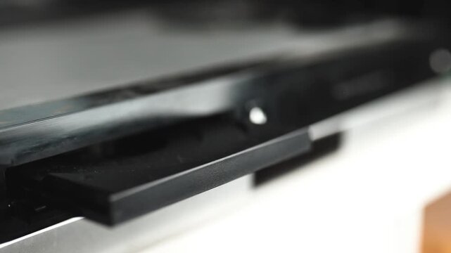 Woman puts a dvd disc into media player.	
