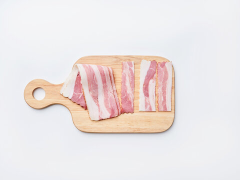 Meat slices are arranged neatly on a wooden board. The setting is bright, indicating daytime. The preparation is likely for a meal or cooking activity in the kitchen