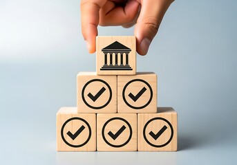 Hand placing a block with a building icon onto a stack of checkmark blocks