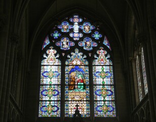 This ornate stained glass window glows within a gothic cathedral, depicting sacred figures in vibrant colors. A symbol of faith and history, ideal for religious or architectural projects.