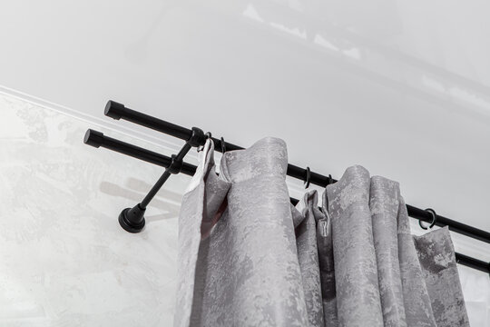 Gray curtains on black curtain rod with rings. Jacquard curtains. Double-row metal curtain rod