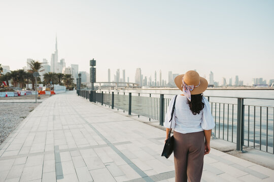 tourist woman looking at Burj Khalifa and Dubai skyline from Dubai Design District promenade
