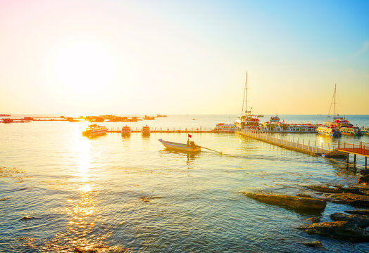Boat moves in sea sunset. Marina with fishing boats at pier. Sunset marina with boats. Calm ocean at coast. Boat sails in sea at sunset with fishing platforms. Fishing boats in sea in bright sunset.