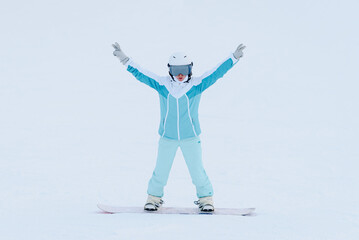 Fototapeta premium young active caucasian woman snowboarding, white and blue sports clothes, white helmet, purple snowboard, sportive woman stands on snowboard, cloudy winter day, mountain slope, equipped ski run