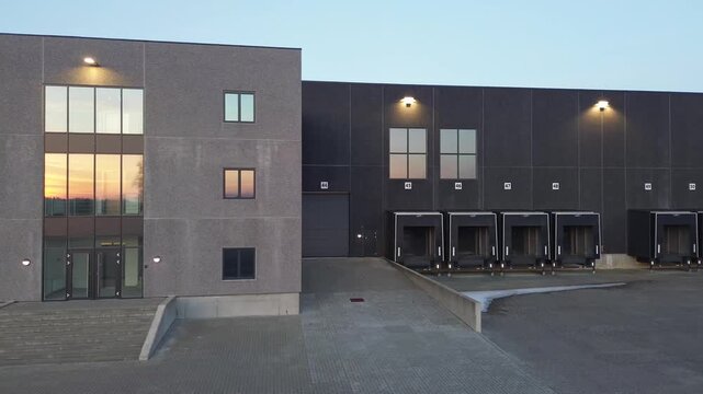 Modern transport center featuring multiple loading docks and an adjacent office building. The clean industrial architecture and organized logistics layout highlight efficiency