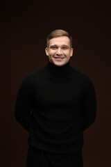Fototapeta premium Fashion model. Portrait of smiling man posing against dark brown background