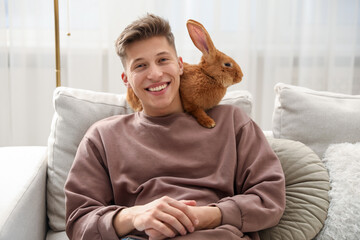 Happy man with cute bunny on sofa at home