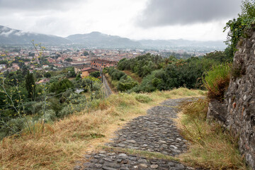 Fototapeta premium a cobbled path leaving the Sarzanello hill with a view over Sarzana city, Province of La Spezia, Liguria, Italy