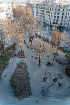Urban Park Square With Bare Trees And People Walking In A City Center
