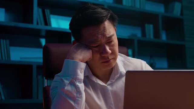 Unhappy Asian 40s business man looking in laptop at night Korean businessman sad with failure work difficulty problem sleepy Japanese male Chinese specialist computer overworked tired late at evening