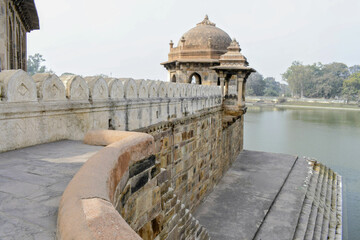 historic stone pavilion and fortified enclosure wall of 'sher shah suri' tomb complex reflected...