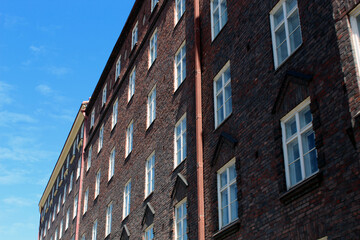 Fototapeta premium Long Brick Apartment Building Facade With Windows And Sky