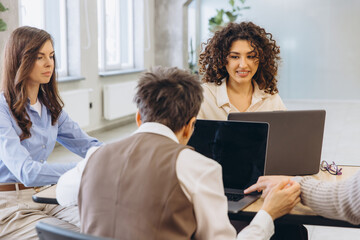 Obraz premium Business colleagues collaborating on laptops, discussing strategy during team meeting in modern office workspace