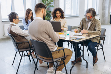 Fototapeta premium Diverse business professionals having a team meeting, collaborating and planning in a modern office environment