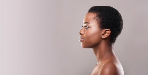 Profile portrait of african american woman with clean flawless skin and short hair looking at copy space on gray background, panorama © Prostock-studio