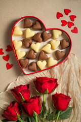 Valentine's Day background, heart gif box with heart chocolates and bouquet of red roses flowers, copy space, flat lay.
