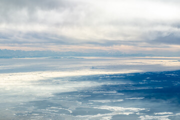 Fototapeta premium Aerial view flying towards alps and clouds during the day