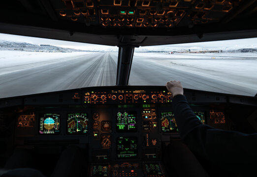Pilot flying commercial airplane from cockpit on snowy runway