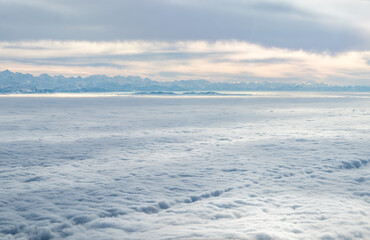 Airplane perspective flying above clouds revealing alps mountains