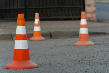 Traffic Cones Block Part of the Road Near a Gated Entrance as a Vehicle Passes by During the Day in an Urban Area
