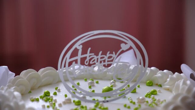 Happy Birthday text. Birthday cake with white cream cheese, cake tier. Delicate lambeth style birthday cake with white cream cheese, festive background with string lights.