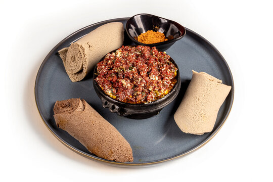 Raw beef or lamb dish Ethiopian kitfo with fluffy  injera flat bread isolated on white
