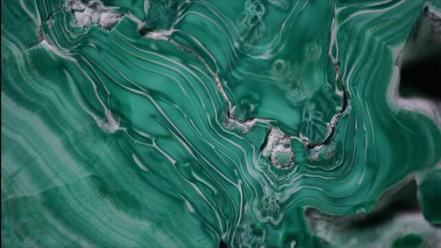 Macro image of polished malachite captured through microscope objective with 15 mm field of view. Banded green and white concentric patterns resembling agate-like structure