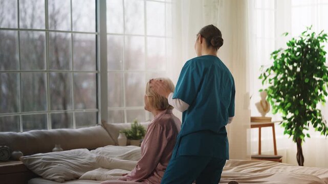 Caring nurse gently combing hair of elderly female patient in nursing home