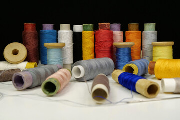 Spools with multi-colored threads on black background, close-up shot