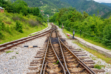 Obraz premium Railway tracks leading through green countryside landscape, representing transportation infrastructure, travel direction, railway logistics, and connection between rural areas.