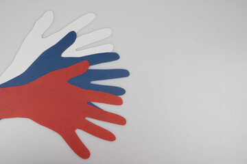Paper hands in white, blue, and red on a light background with space for your text