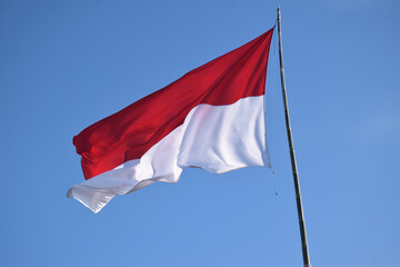 Naklejka premium The Indonesian red and white flag against a blue sky 