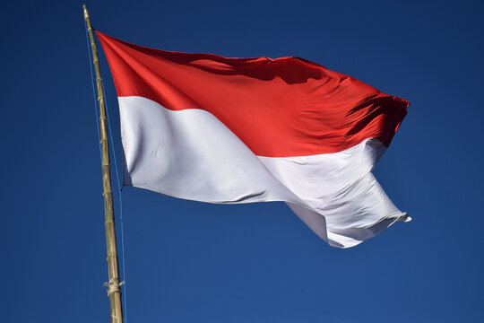 The Indonesian red and white flag against a blue sky
