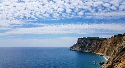 Obraz premium Serene cliffside by the ocean with a vast blue sky and scattered clouds