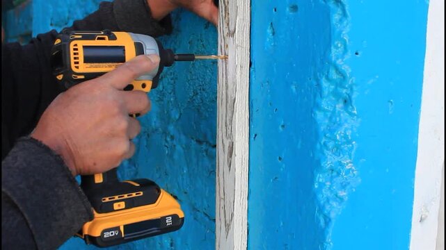 HOMBRE PERFORANDO UNA TABLA DE MADERA CON TALADRO ELECTRICO