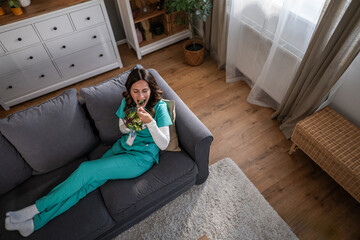 Obraz premium Healthcare worker eating healthy salad on sofa during break