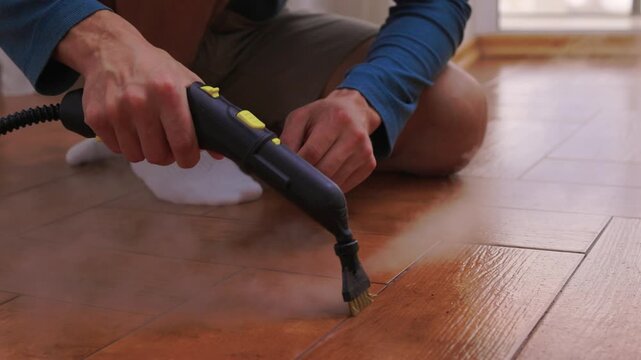 Floor cleaning detail. Technician delicately removing dirt from shiny floor grout lines. Modern apartment floor restoration with precise nozzle and softening vapor techniques