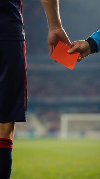 Referee shows a red card to a soccer player on the field during a match