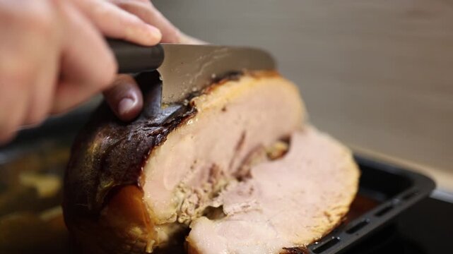 Close up of freshly baked pork knuckle being sliced with knife juicy meat texture cinematic food preparation at home festive dinner atmosphere