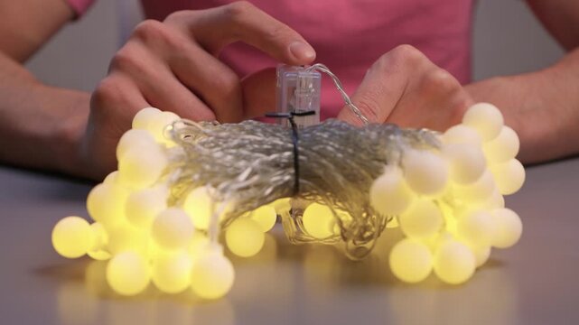 Demonstration of Garland Lights in Use. Showing How Battery Controller Turns On String Lights. Detailed View of Hand Operation and Bulb Transition for Ambient Decoration