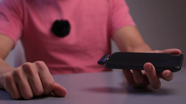 Lavalier attachment to phone for rapid interview recordings. Onsite interview preparation involving portable microphone and quick assembly tools in natural lighting conditions