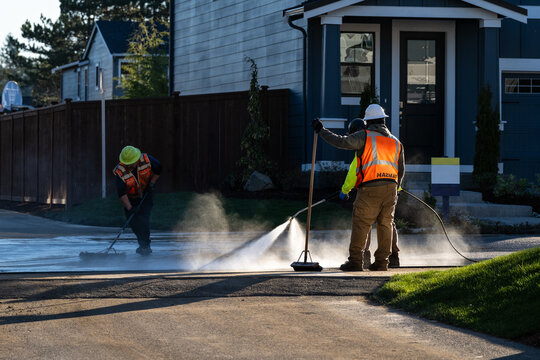 Specialized hazardous materials response team, hazmat cleanup of spilled chemicals on residential housing development job site, workmen with pressure sprayer and broom
