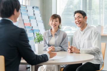 Fototapeta premium A couple listening to a conversation in a showroom/negotiation space and a businessman serving them