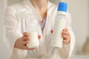 Fototapeta premium Woman with breast pump and bottle of milk in bedroom, closeup