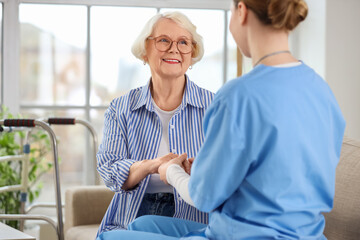 Obraz premium Caregiver and senior woman sitting on sofa in nursing home