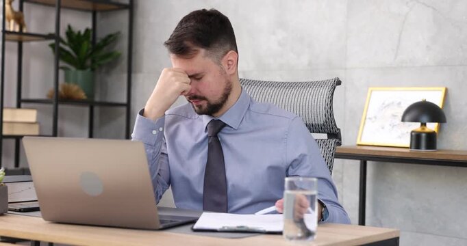 Man feeling fatigue at wooden desk in office