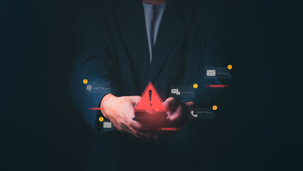 Businessman holding a smartphone with a large red warning triangle and multiple digital alert...