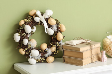 Easter wreath with books on fireplace near green wall, closeup