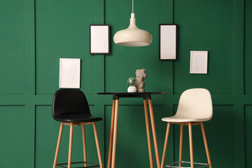 Naklejka premium Interior of modern stylish room with chairs and table near green wall