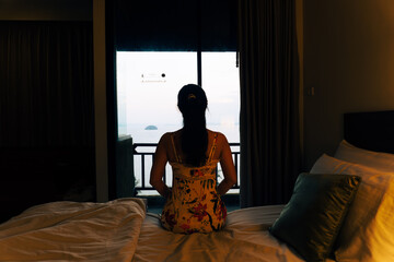 Young woman in a bedroom looking out to the sea view